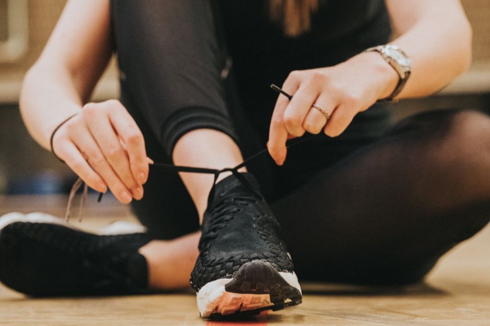 Een studente uit de educatieve bachelor LO en bewegingsrecreatie strikt haar veters tijdens het sporten.