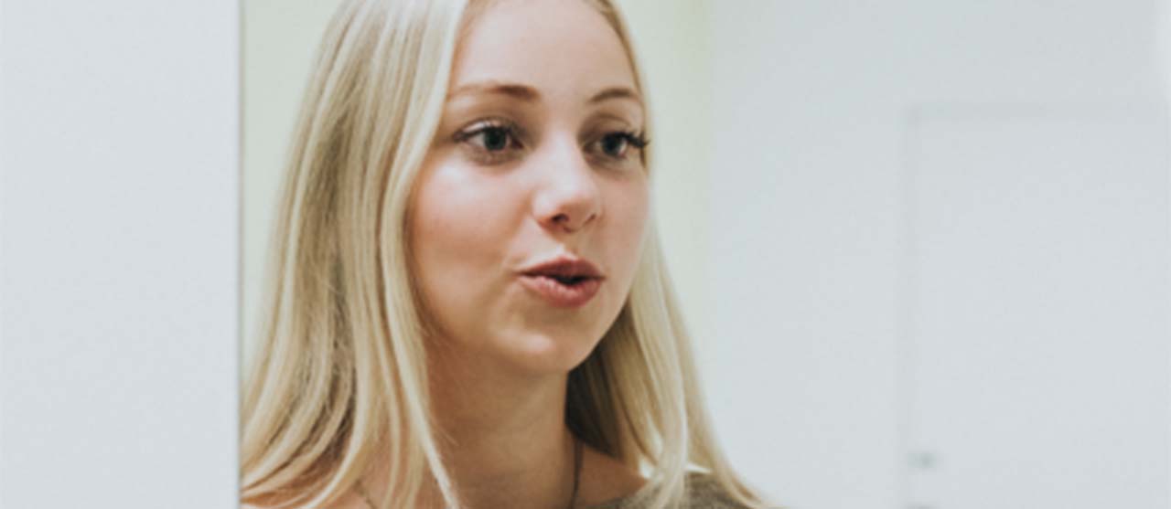 Een studente uit de afstudeerrichting logopedie van de bachelor logopedie en audiologie oefent mondbewegingen voor de spiegel.