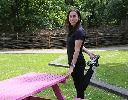 Personal trainer Dempsey Demeyer stretchtend aan een picknickbank.