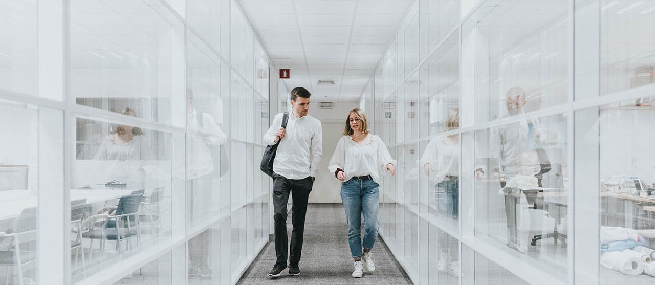 Een student milieu- en duurzaamheidsmanagement van HOGENT wandelt langs textiellabo's tijdens een bezoek aan een textielbedrijf.