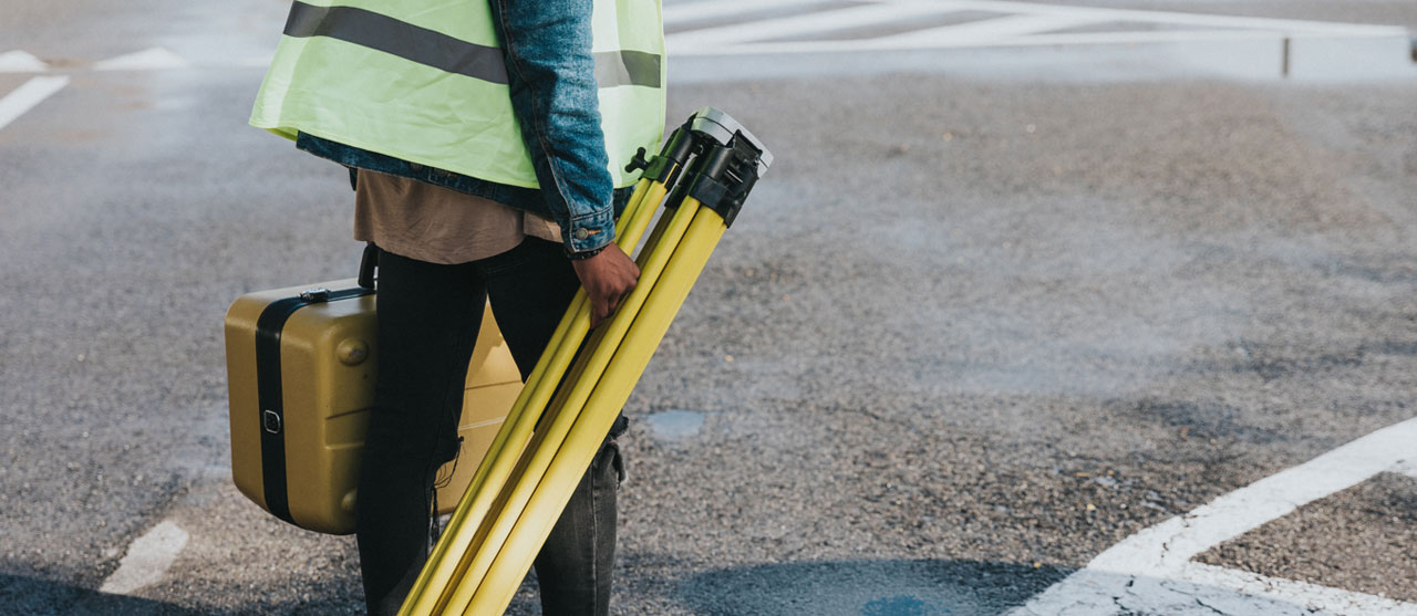 Een student uit de graduaatsopleiding bouwkundig tekenen aan HOGENT loopt rond met een topografisch toestel om constructies te gaan opmeten.
