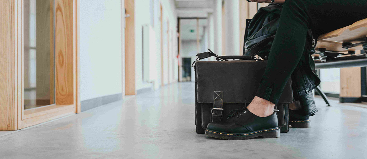 Student modetechnologie van HOGENT zit op een bank en bekijkt zijn smartphone.