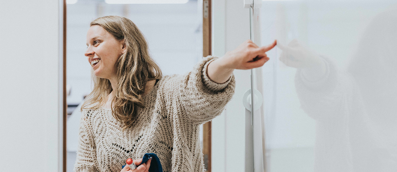 leerkracht wijst naar white board