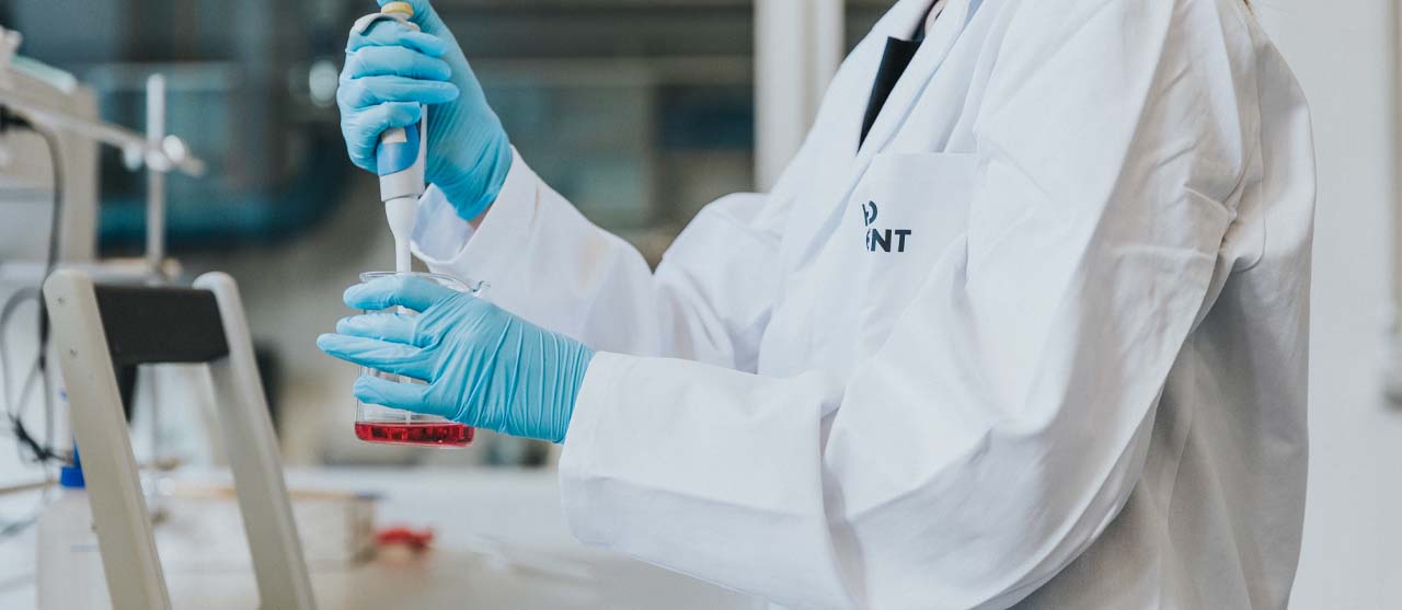 Een student uit de afstudeerrichting chemie van de bachelor chemie pipetteert een vloeistof in een erlenmeyer in het labo.