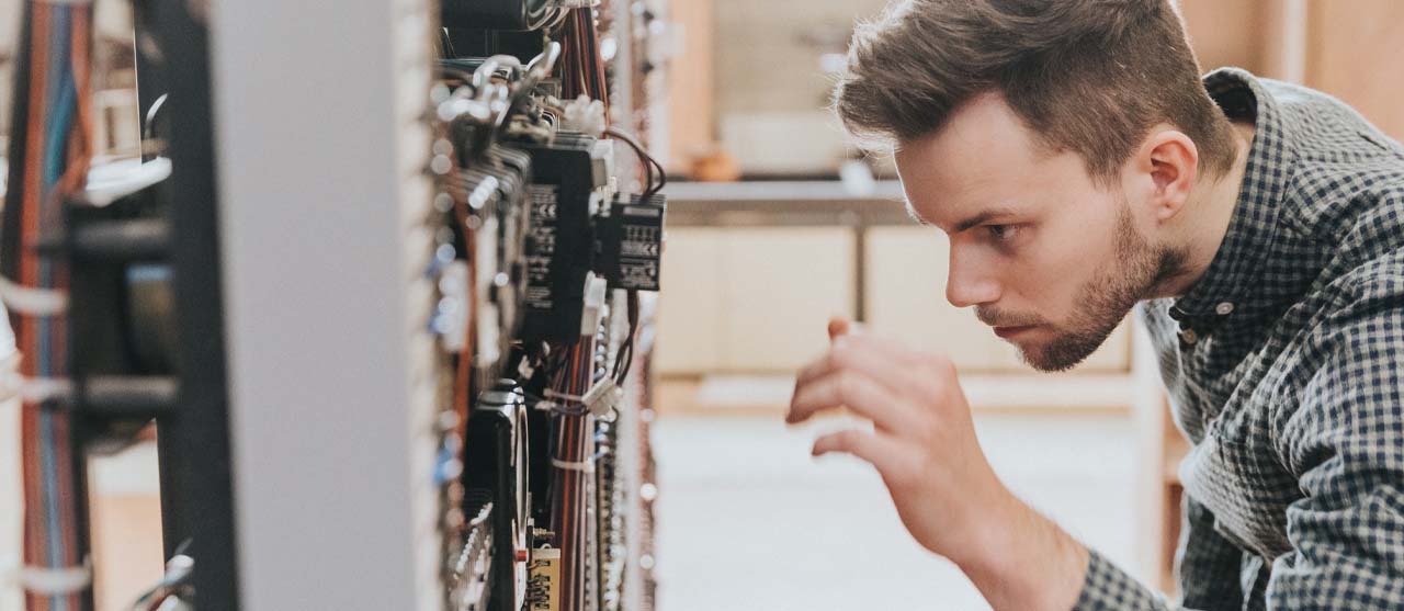Een student uit de bachelor elektromechanica van HOGENT bestudeert een elektriciteitskast in een praktijkles.