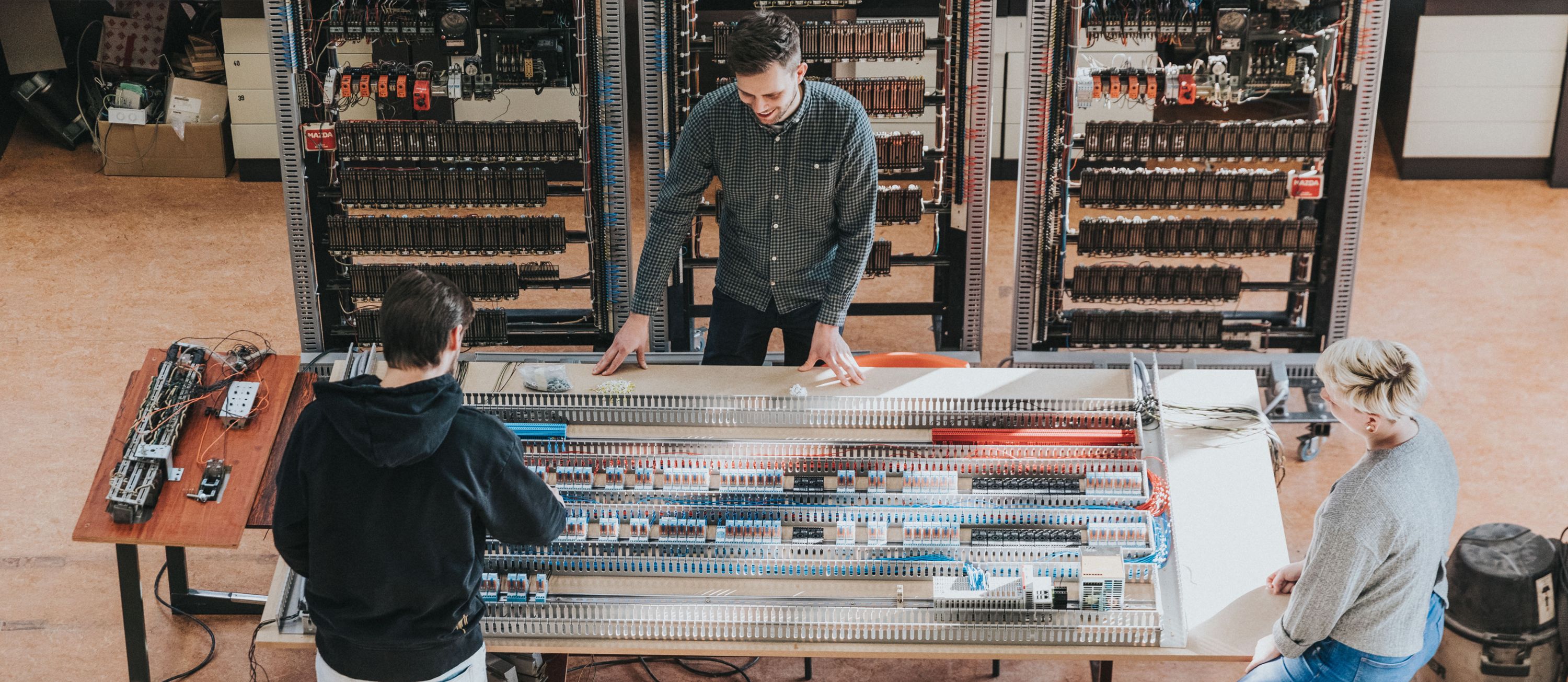 Drie studenten uit de opleiding HVAC-systemen werken samen aan een elektrische installatie tijdens hun opleiding op HOGENT campus Schoonmeersen.
