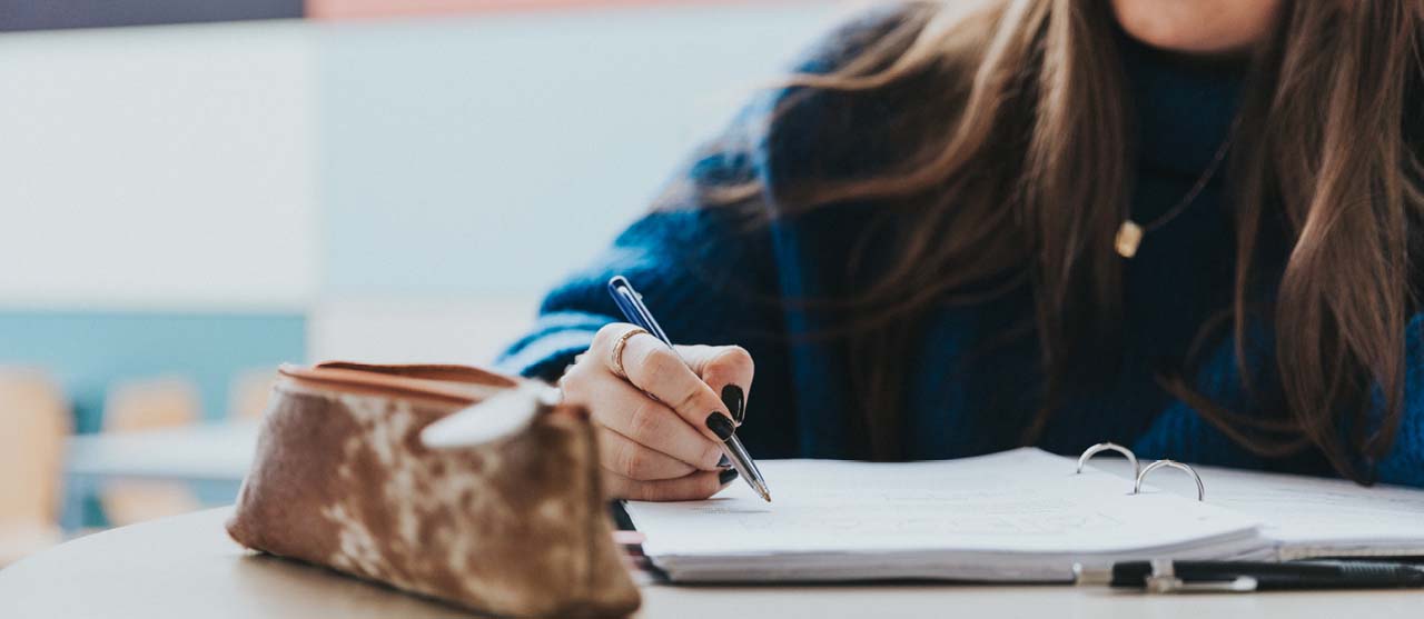 Studente International Communication van HOGENT neemt notities tijdens de les.