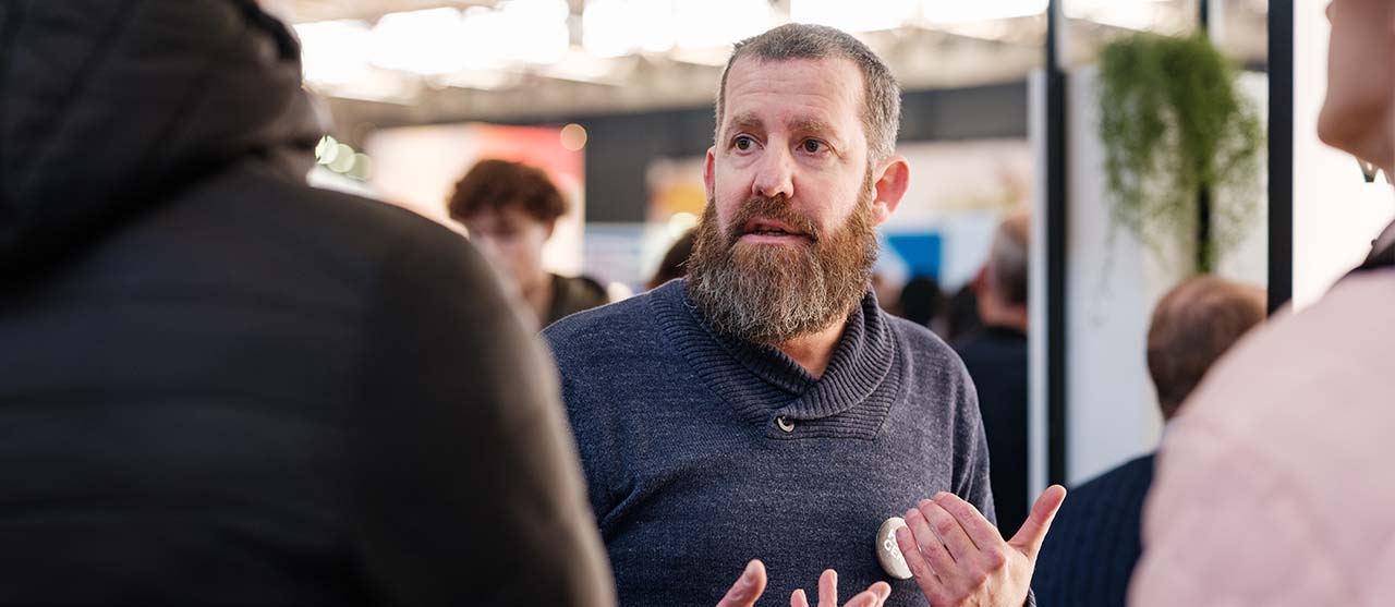 Een lesgever in gesprek met geïnteresseerden in vastgoed.