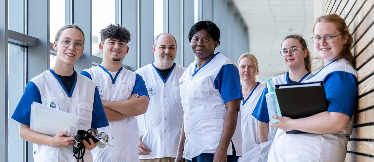 Twee studenten uit het graduaat basisverpleegkunde wandelen lachend door een ziekenhuisgang.